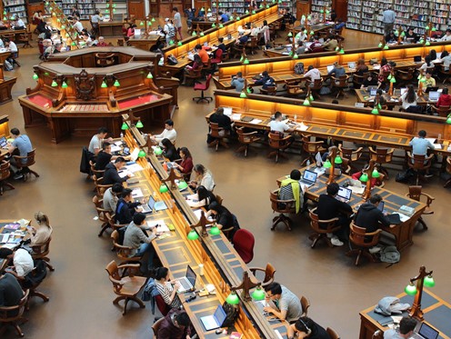Old-style library filled with people sat at desks poring over books