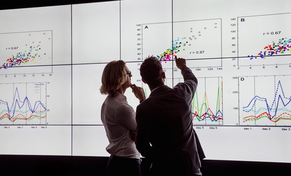 Woman and man in business clothes pointing at graphs