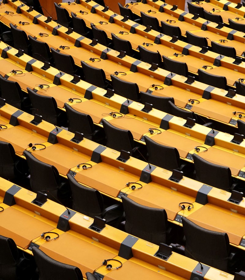 Rows of empty seats from a parliament hemicycle with headphones on desks and electronic voting equipment fitted